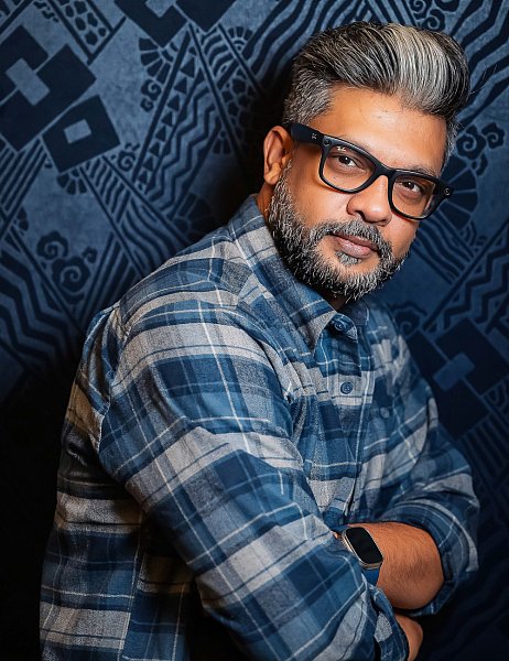 executive speaker Man in blue flannel shirt wearing Ray‑Ban glasses. 